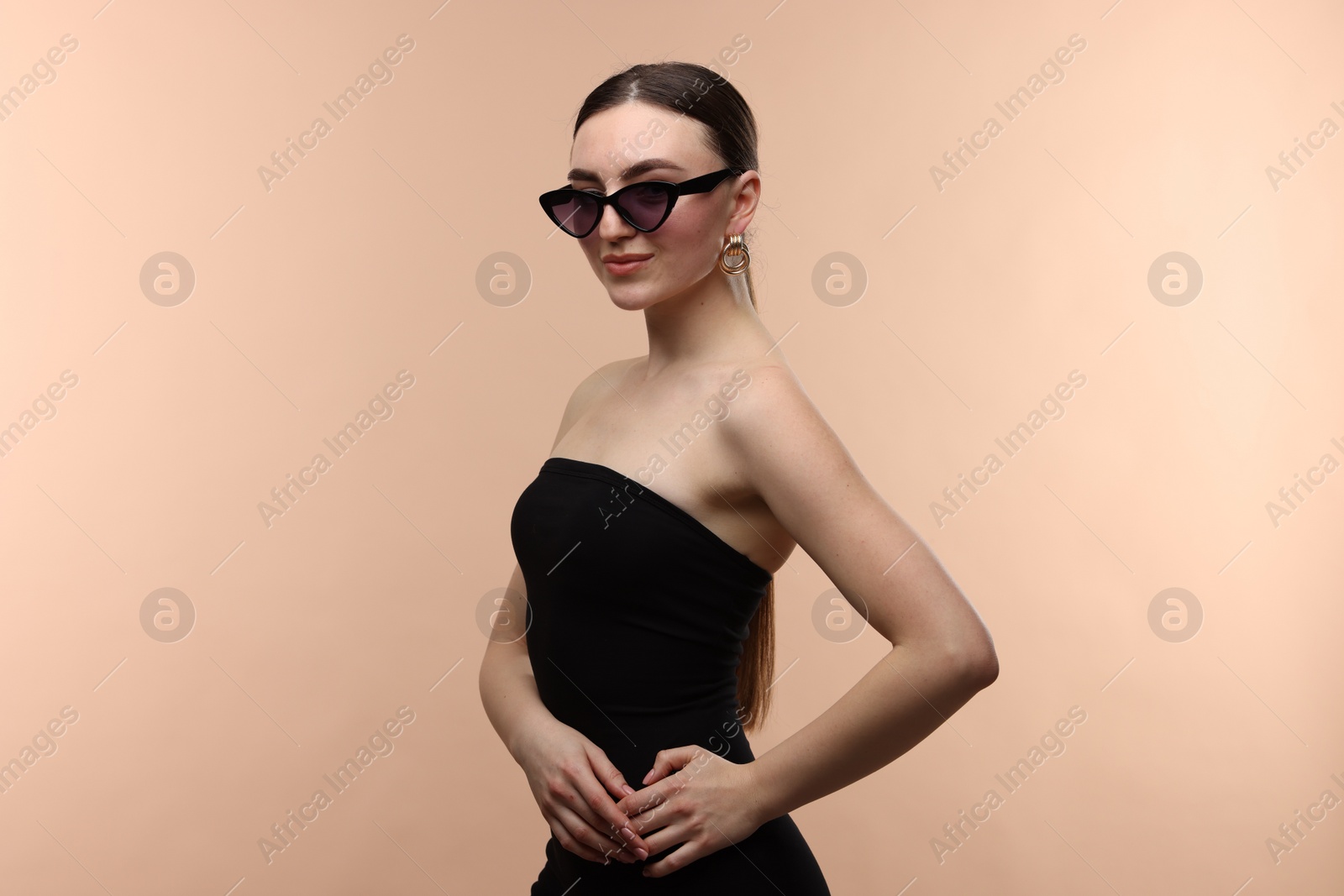 Photo of Portrait of beautiful young woman with sunglasses on beige background