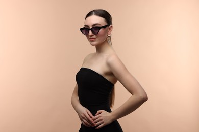 Photo of Portrait of beautiful young woman with sunglasses on beige background