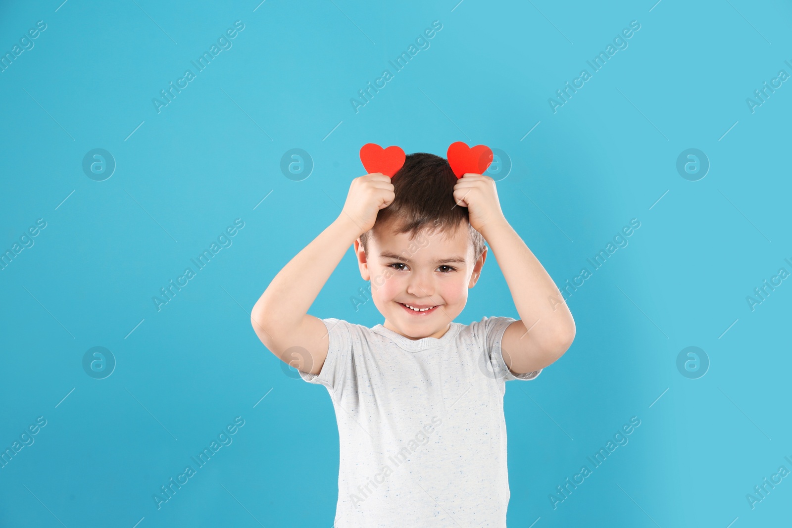 Photo of Portrait of boy with paper hearts on color background