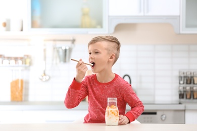 Little boy with yogurt in kitchen