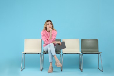 Photo of Young woman with tablet waiting for job interview on light blue background
