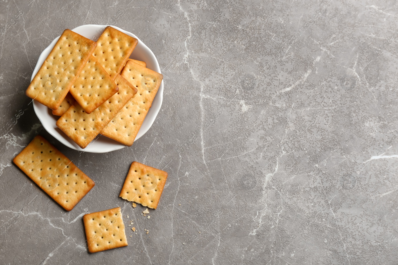 Photo of Delicious crispy crackers on grey table, flat lay. Space for text