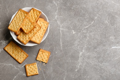 Photo of Delicious crispy crackers on grey table, flat lay. Space for text