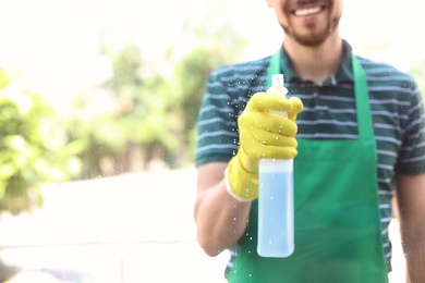 Male worker washing window glass from outside