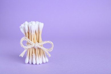 Photo of Bunch of wooden cotton buds on violet background. Space for text