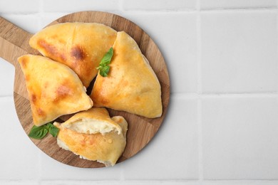 Delicious samosas and basil on white tiled table, top view. Space for text