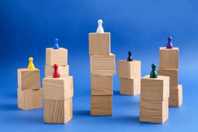 Photo of Wooden blocks with color playing pieces on blue background. Roles and responsibility concept