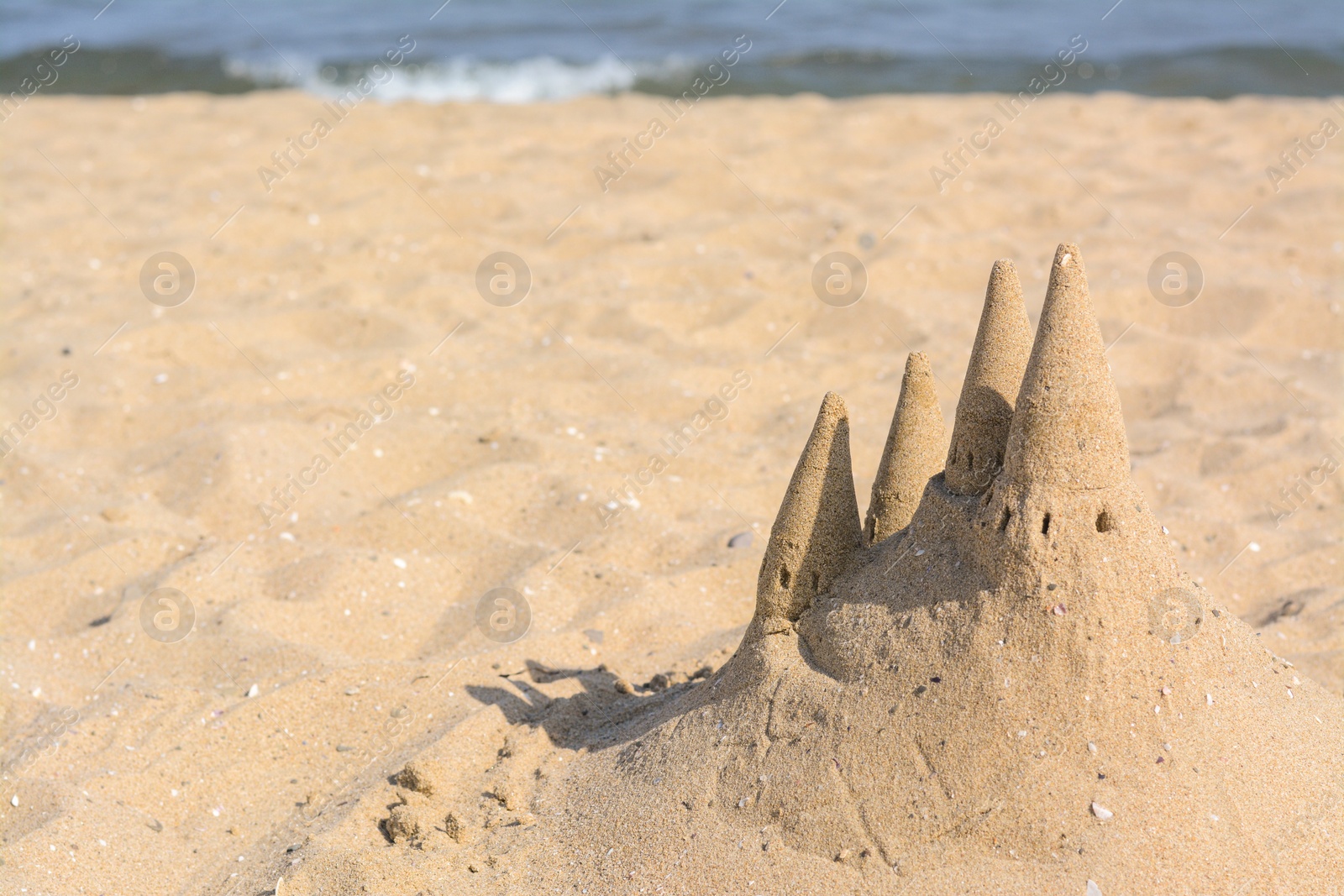 Photo of Beach with sand castle near sea on sunny day. Space for text