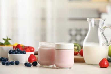 Photo of Portion jars for yogurt maker and different fruits on white wooden table in kitchen