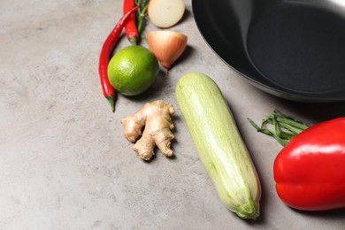 Empty iron wok and raw ingredients on grey table. Space for text