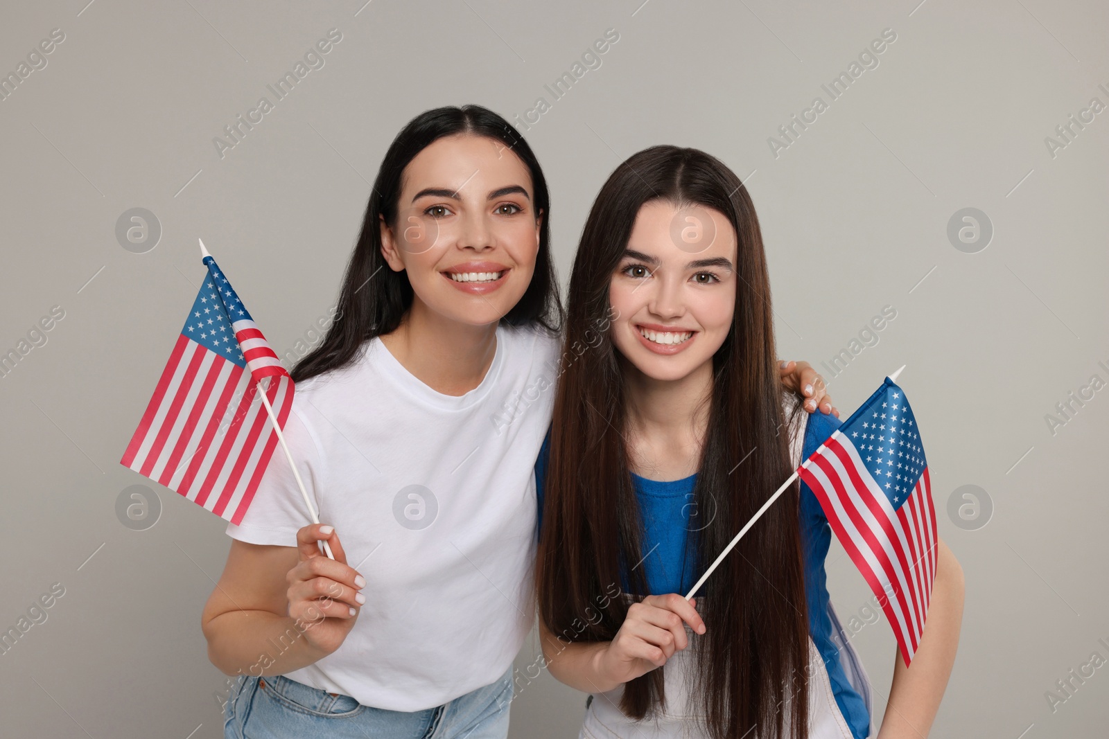 Photo of 4th of July - Independence Day of USA. Happy woman and her daughter with American flags on light grey background