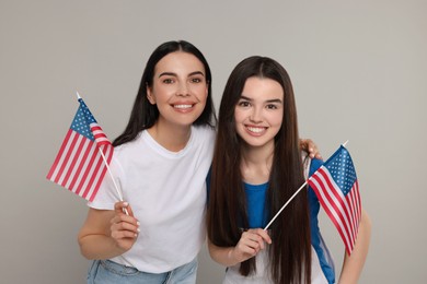 Photo of 4th of July - Independence Day of USA. Happy woman and her daughter with American flags on light grey background