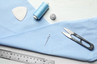 Flat lay composition with accessories for tailoring on wooden table