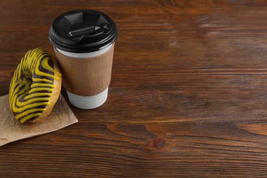 Tasty frosted donut and hot drink on wooden table, space for text