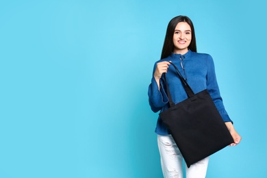 Photo of Beautiful young woman with stylish blank eco bag against color background, space for text