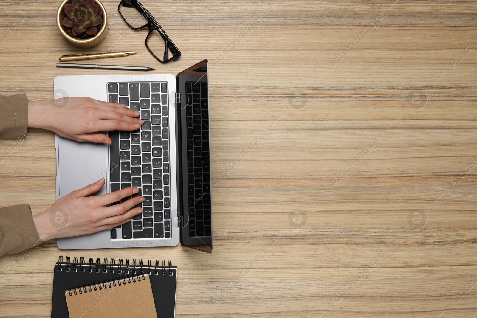 Photo of Woman using laptop at wooden table, top view. Space for text