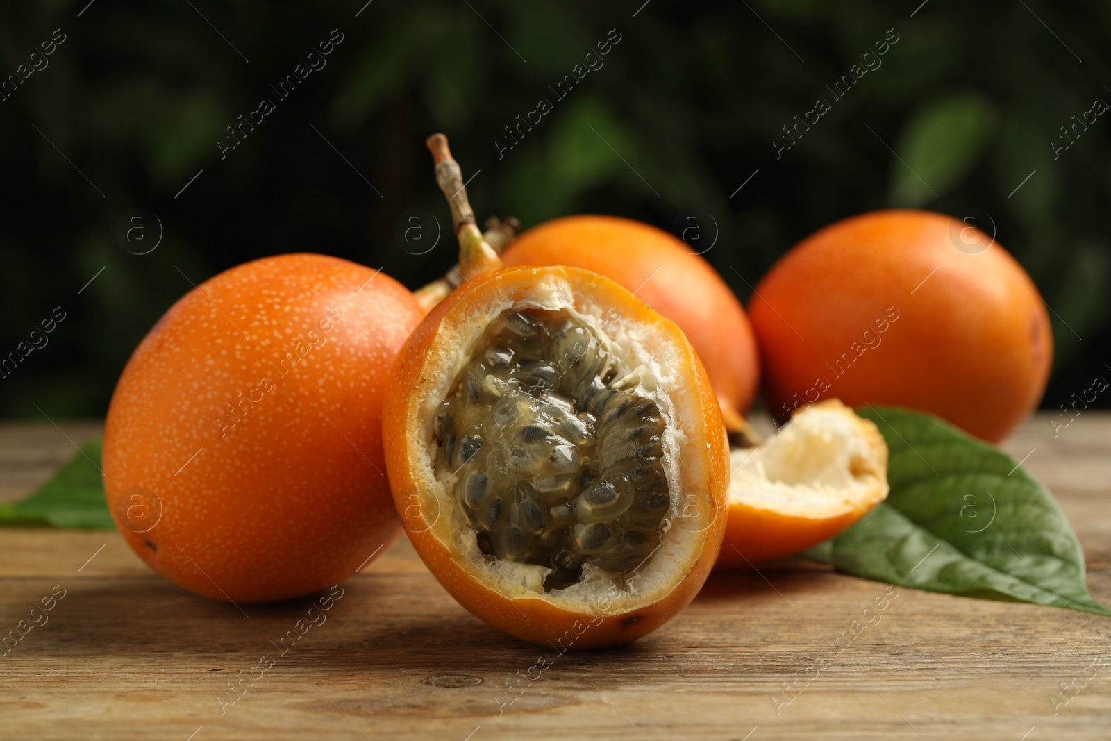 Photo of Delicious ripe granadillas on wooden table, closeup