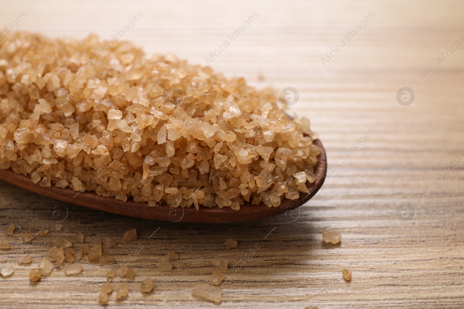 Photo of Wooden spoon with salt for spa scrubbing procedure on wooden table, closeup