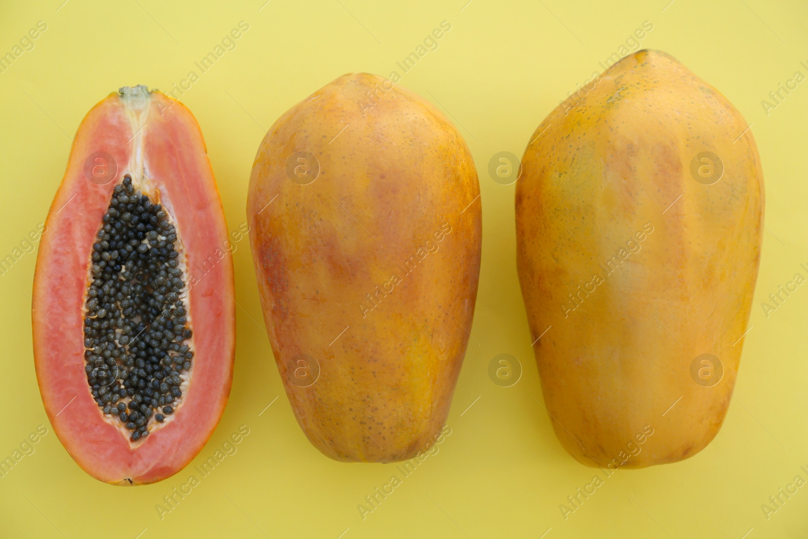 Photo of Fresh ripe cut and whole papaya fruits on light green background, flat lay