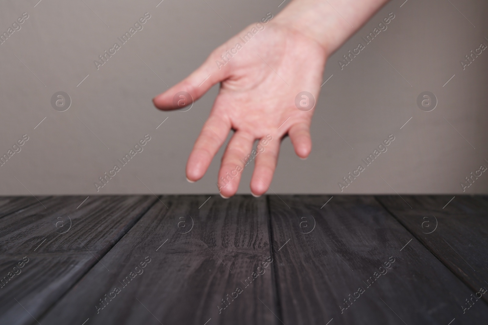 Photo of Woman holding hand above black wooden table, selective focus. Space for text