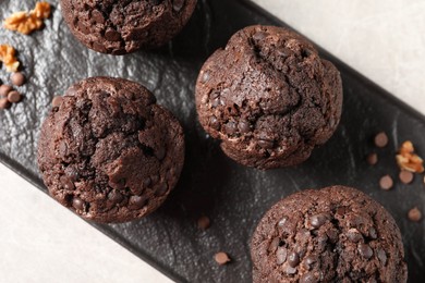 Delicious chocolate muffins on light table, top view