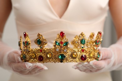 Photo of Bride holding luxurious crown on grey background, closeup view