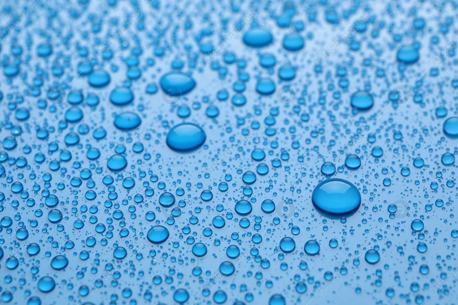 Photo of Water drops on light blue background, closeup view