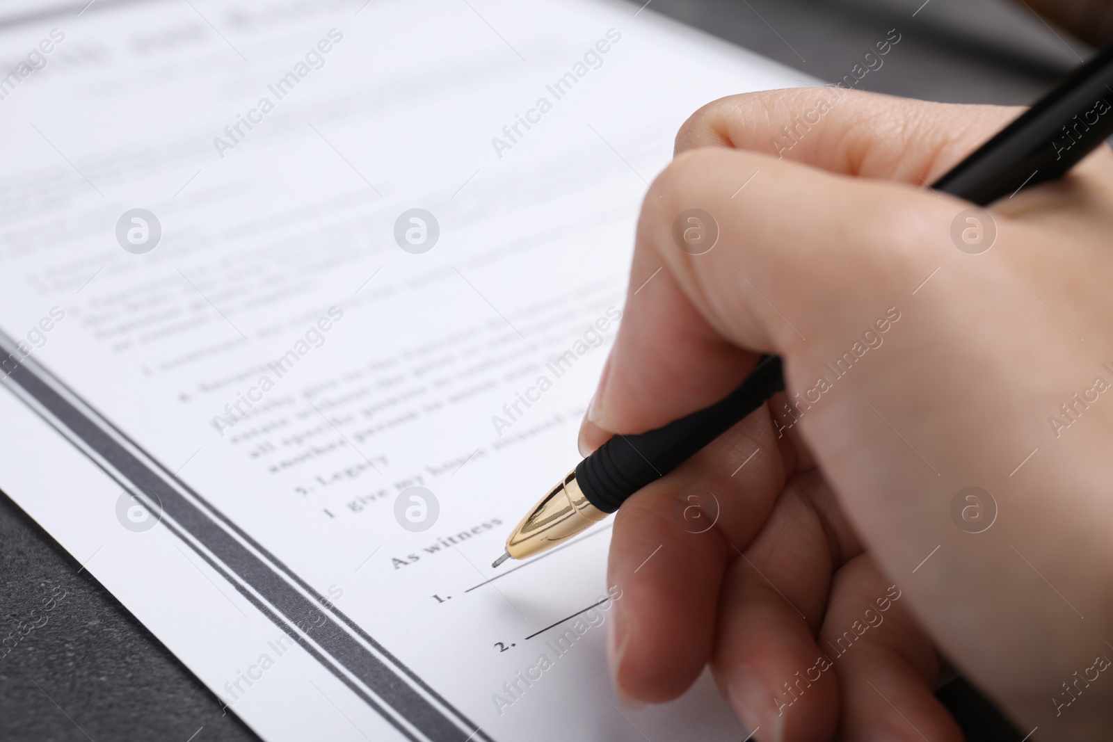 Photo of Woman signing last will and testament at grey table, closeup