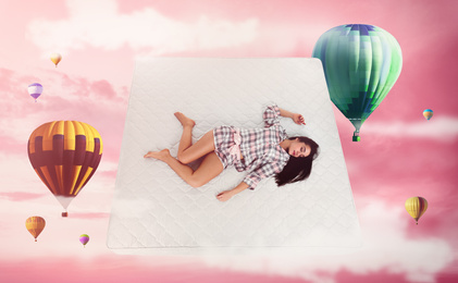 Image of Sweet dreams. Pink cloudy sky with hot air balloons around sleeping young woman 