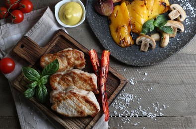 Delicious grilled meat and vegetables served on wooden table, flat lay. Space for text