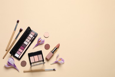 Photo of Flat lay composition with different makeup products and beautiful flowers on beige background. Space for text