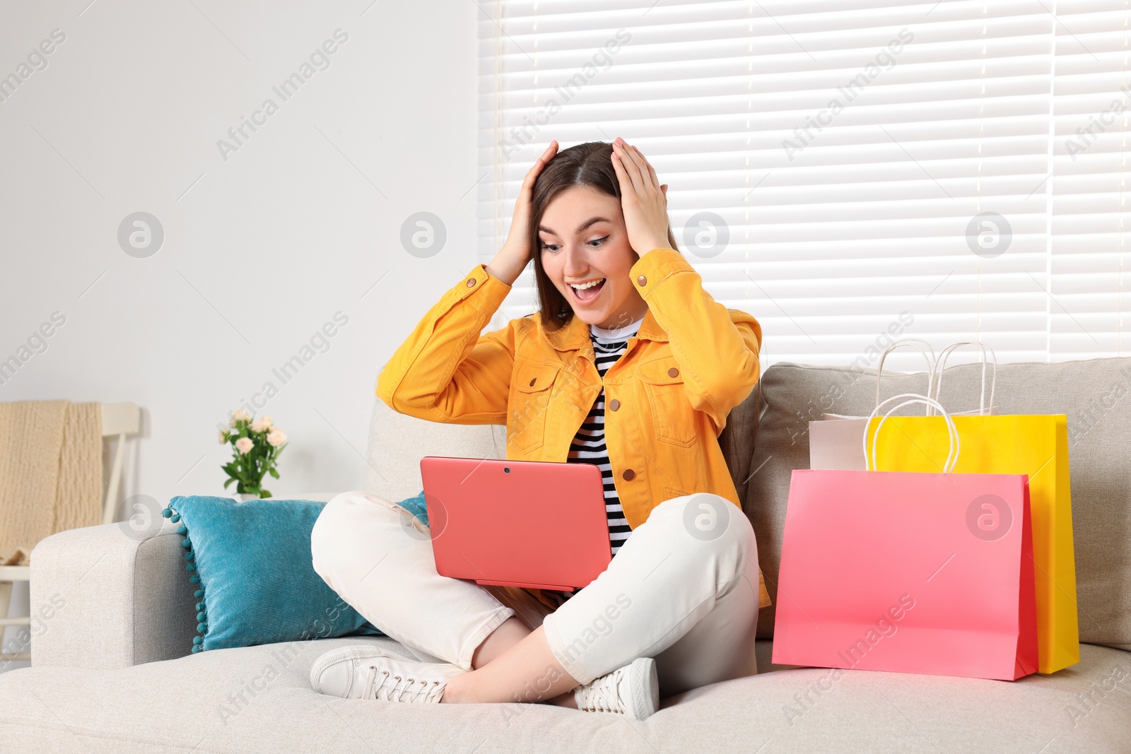 Photo of Special Promotion. Emotional woman looking at laptop on sofa indoors