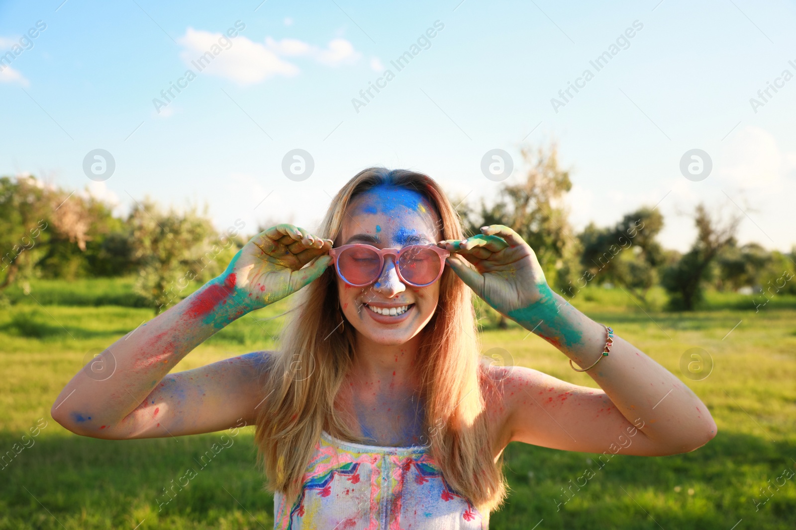 Photo of Happy woman covered with colorful powder dyes outdoors. Holi festival celebration