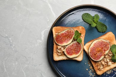 Tasty toasts with fig pieces, peanut butter and walnuts on light grey marble table, top view. Space for text