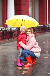 Photo of Mother and daughter with umbrella in city on autumn rainy day