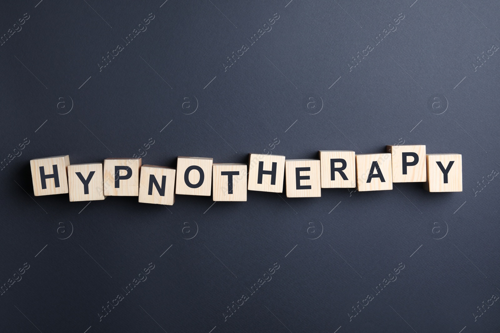 Photo of Wooden blocks with word HYPNOTHERAPY on black background, flat lay