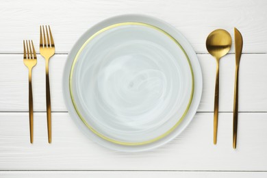 Stylish setting with cutlery and plate on white wooden table, flat lay