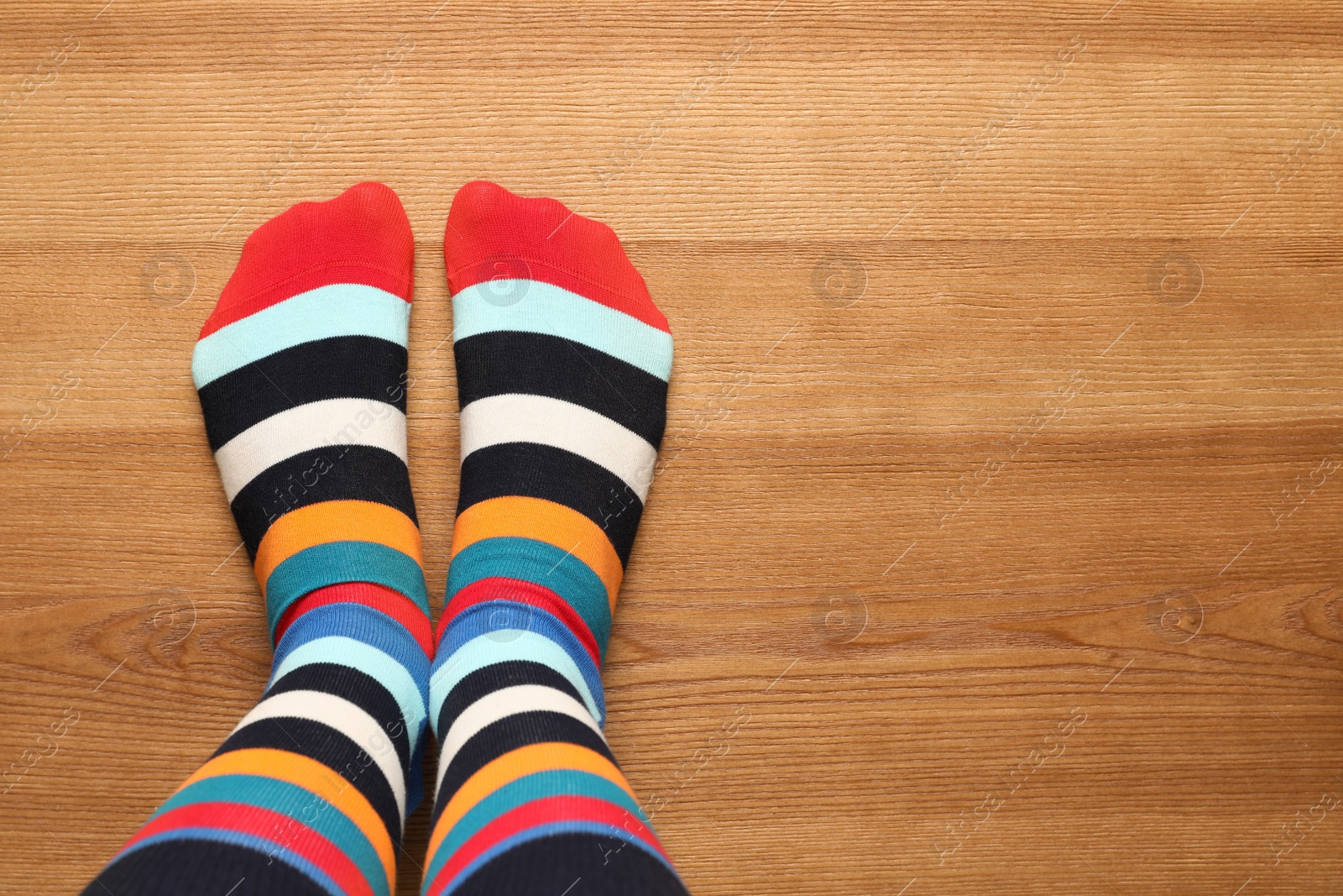 Photo of Woman wearing stylish socks standing on floor, top view. Space for design