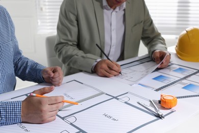 Architects working with construction drawings at table in office, closeup