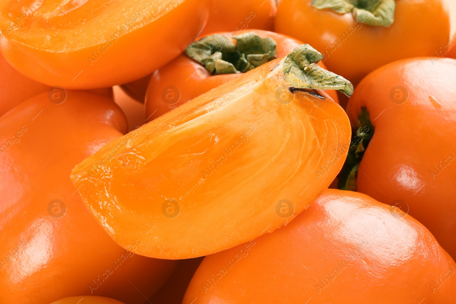 Photo of Whole and cut delicious ripe juicy persimmons as background, closeup