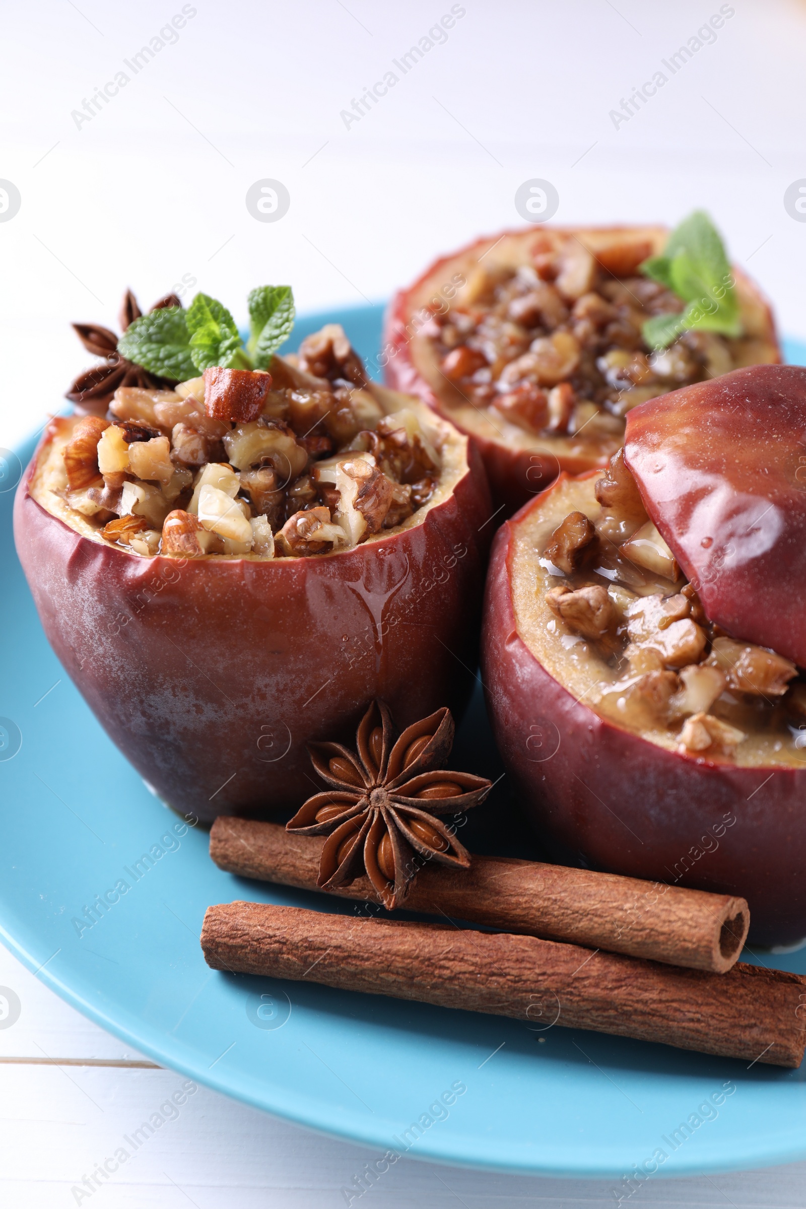 Photo of Tasty baked apples with nuts, honey, spices and mint on white wooden table, closeup