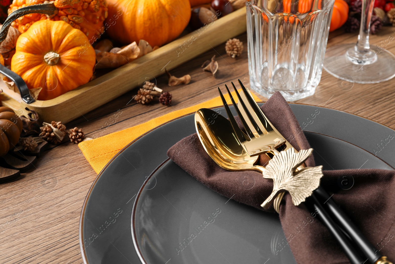 Photo of Thanksgiving table setting. Plates, cutlery, glasses and autumn decor