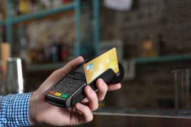 Photo of Man using credit card machine for non cash payment in cafe, closeup. Space for text