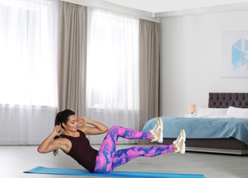 Photo of Young woman in fitness clothes doing exercise at home. Space for text