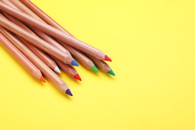 Photo of Many colorful pastel pencils on yellow background, closeup with space for text. Drawing supplies