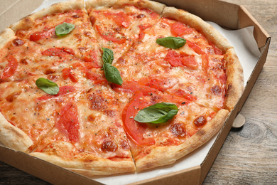 Photo of Delicious pizza Margherita on wooden table, closeup view