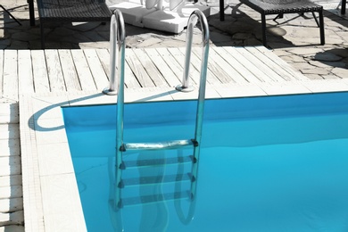 Modern swimming pool with step ladder outdoors