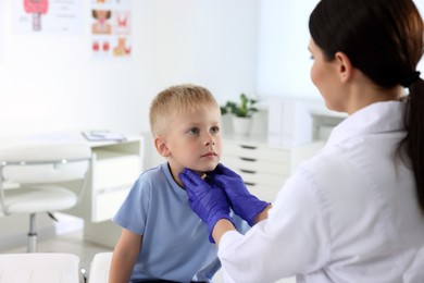 Endocrinologist examining boy's thyroid gland at hospital