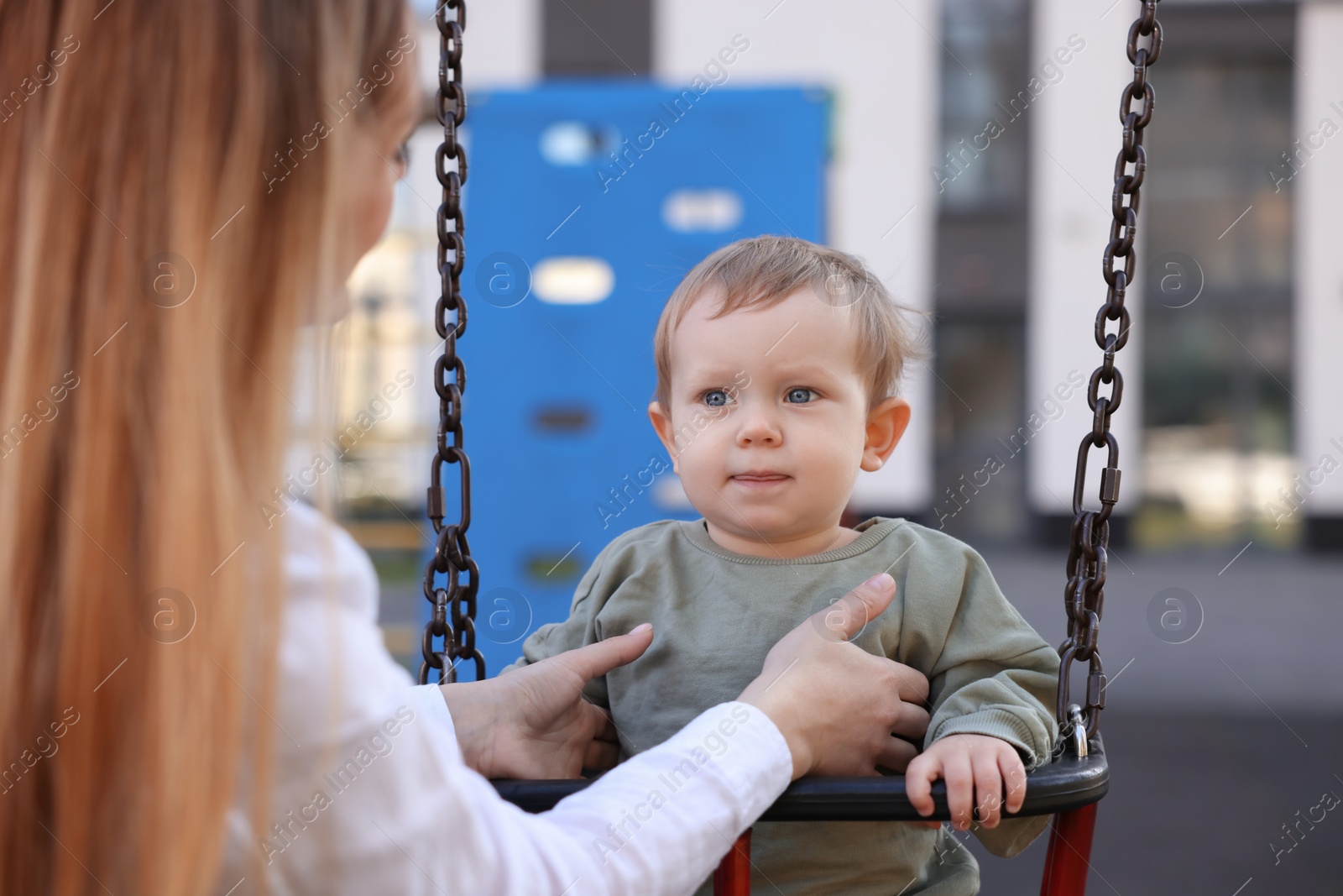 Photo of Nanny and cute little boy on swing outdoors