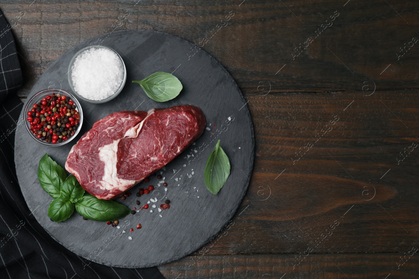 Photo of Fresh raw cut beef, spices and basil leaves on wooden table, top view. Space for text